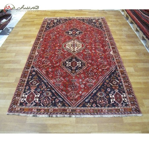 فرش دستبافت شیراز کد 39244 دارای الیاف طبیعی، طرح لچک و ترنج با رنگ زمینه لاکی و حاشیه سرمه ای